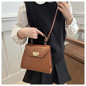 Détail du sac à main en cuir marron caramel avec fermoir rotatif doré et poignée solide