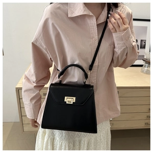 Detail of glossy black leather handbag with elegant gold rectangular twist lock closure