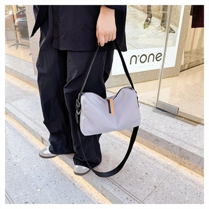 Outdoor street shot of large purple nylon messenger bag with orange zipper detail