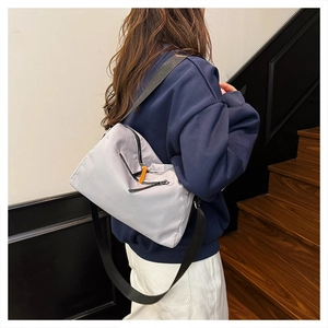 Close-up of light purple nylon messenger bag with orange zipper pull and black strap
