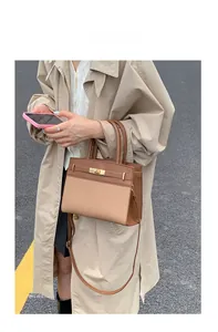 Detail of elegant brown leather and canvas Kelly bag with golden buckle on a model