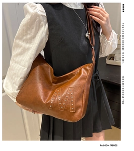 Detailansicht der braunen Hobo-Tasche mit Nieten-M-Design und matter Lederstruktur