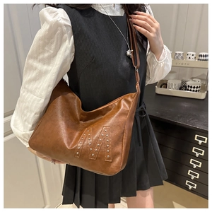 Detailansicht der braunen Vintage-Einkaufstasche mit Nieten-M-Muster für Damen