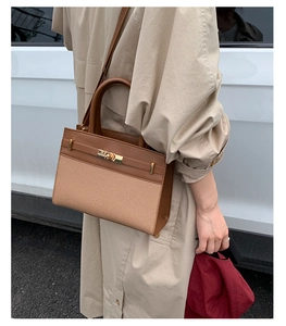 Brown leather and canvas handbag detail showing metal buckle and side stitching