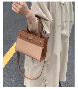 Brown leather and canvas crossbody bag worn by a model in a street style setting