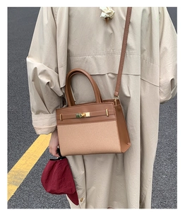 Close-up of stylish brown leather and beige canvas handbag with gold metal clasp detail