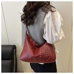 Detail der vintage dunkelroten Tragetasche mit M-Patch und Metallnieten am Modell