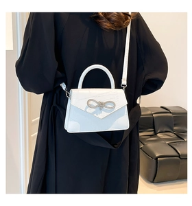Close-up of white crocodile pattern shoulder bag with a silver diamond bow lock detail