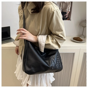 Detail der schwarzen Hobo-Tasche aus Leder mit silbernen Nieten im M-Design-Stil