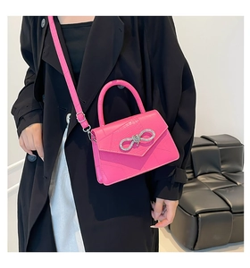 Close-up of bright pink faux crocodile handbag with sparkling rhinestone bow detail
