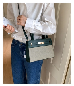 Detail of a chic dark green leather and beige canvas handbag with gold hardware