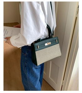 Detail of green leather and beige canvas crossbody bag with gold metal twist lock buckle