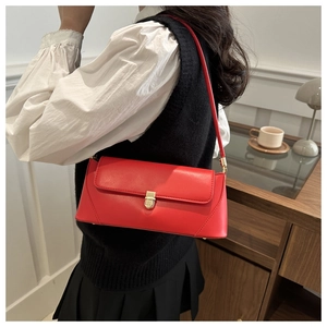 Detail of red leather shoulder bag showing the golden metal buckle and smooth stitching