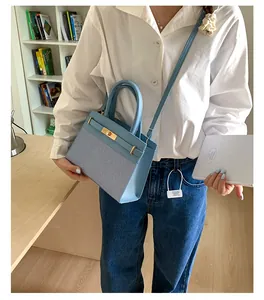 Detail of light blue patchwork handbag featuring textured fabric and gold turn-lock closure