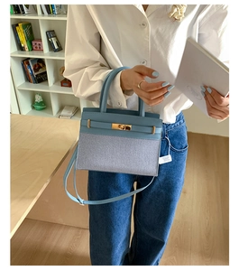 Detail of light blue crossbody bag featuring gold twist lock and leather strap accents