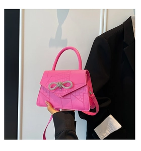 Detail of rose pink crocodile embossed handbag with sparkling crystal bow buckle and handle