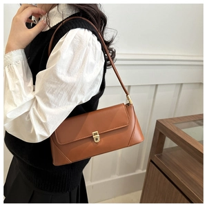 Classic brown baguette bag with golden metal buckle and slim shoulder strap on model