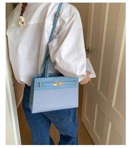 Detail of light blue crossbody bag with woven texture, gold twist lock and shoulder strap