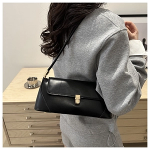 Detail of minimalist black baguette bag with gold metal buckle on female model