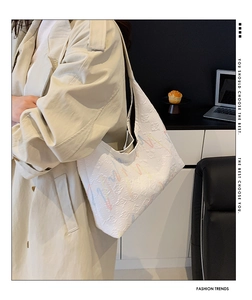 Detail showing the white textured fabric and colorful wavy embroidery on the tote bag