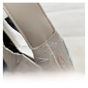 Close-up of neat stitching on beige lychee leather strap and woven textured fabric