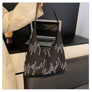 Detail of black embossed tote bag featuring contrast zigzag wave stitching and wide strap
