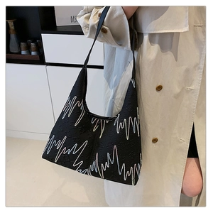 Detail of black hobo bag featuring colorful zigzag embroidery and pleated texture on the body