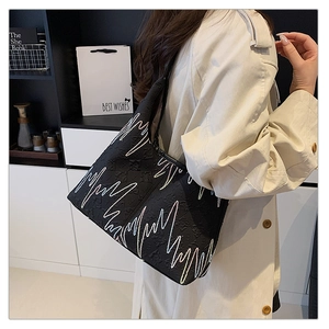 Detail of black tote bag featuring colorful wavy embroidery and textured fabric finish