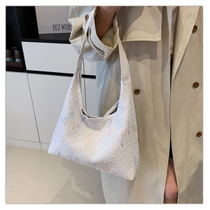 Detail of white leather shoulder bag with embroidered wavy lines on beige trench coat