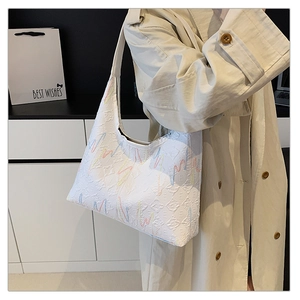 Detail view of white embossed leather handbag with vibrant colorful embroidered wavy lines