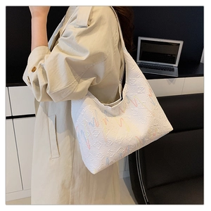 Detail of white tote bag featuring colorful wavy embroidery and textured fabric