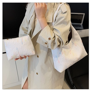 Fashionable white embossed tote bag set with colorful lines worn on shoulder by model