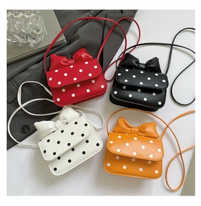 Detailed view of mini polka dot crossbody bags in four colors with large bow accents