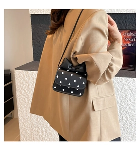 Polka dot shoulder bag with large leather bow detail shown on a model side view