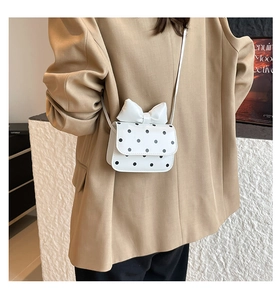 Close-up of a white polka dot mini crossbody bag with a cute 3D bow on the flap