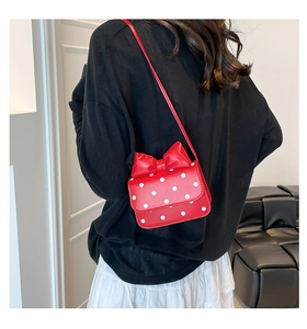 Detailed view of red polka dot mini bag with bow on model showing back placement