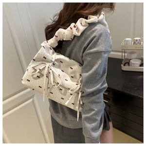 Detail of white cloud bag with red bow print and ruched shoulder strap in a cozy setting
