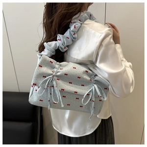 Detail of light blue floral bag showing ruffled shoulder straps and ribbon drawstrings