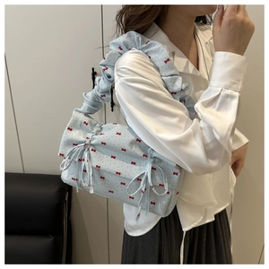 Detail of light blue shoulder bag with red bow prints and ruffled gathered handle