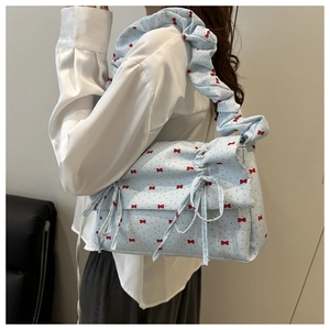Detail of light blue pleated shoulder bag with red polka dots and bow decorations