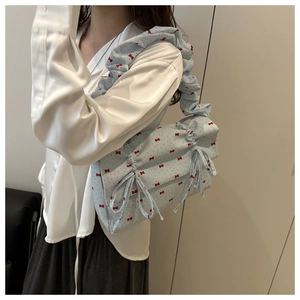 Detail of light blue ruffled underarm bag featuring red bow prints and drawstring