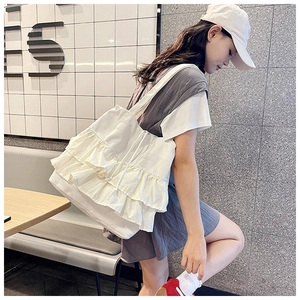 Detail of white pleated canvas tote bag featuring ruffled edges and adjustable drawstrings