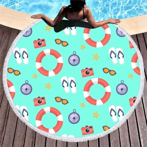 Round beach towel with summer travel icons and white tassels on a blue poolside background