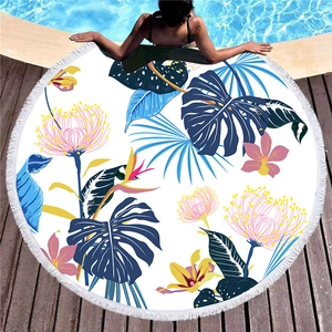 Round thick beach towel with tropical floral print, blue palm leaves and white tassels