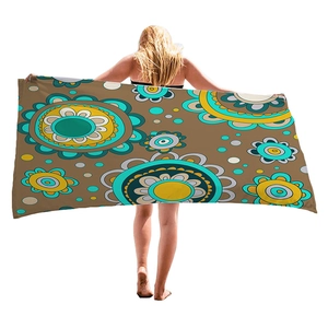 Brown beach towel with mandala patterns held by a model on a white background