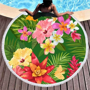 Rundes Strandtuch mit tropischem Blumenmuster und weißen Fransen am Pooldeck aus Holz