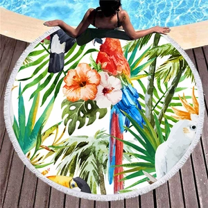 Round tropical beach towel with parrot prints and white tassels on pool deck
