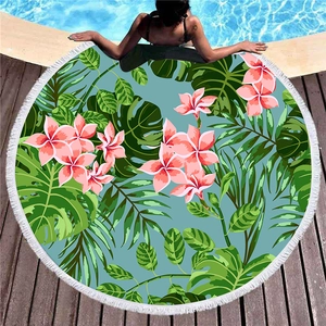 Round tropical beach towel with fringe edge featuring monstera leaves and frangipani print