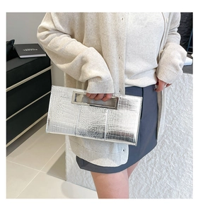 Detail of silver crocodile texture handbag with integrated metallic top handle