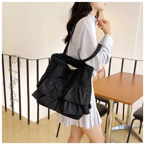 Detail of a large black tote bag with unique layered ruffles and pleated canvas texture